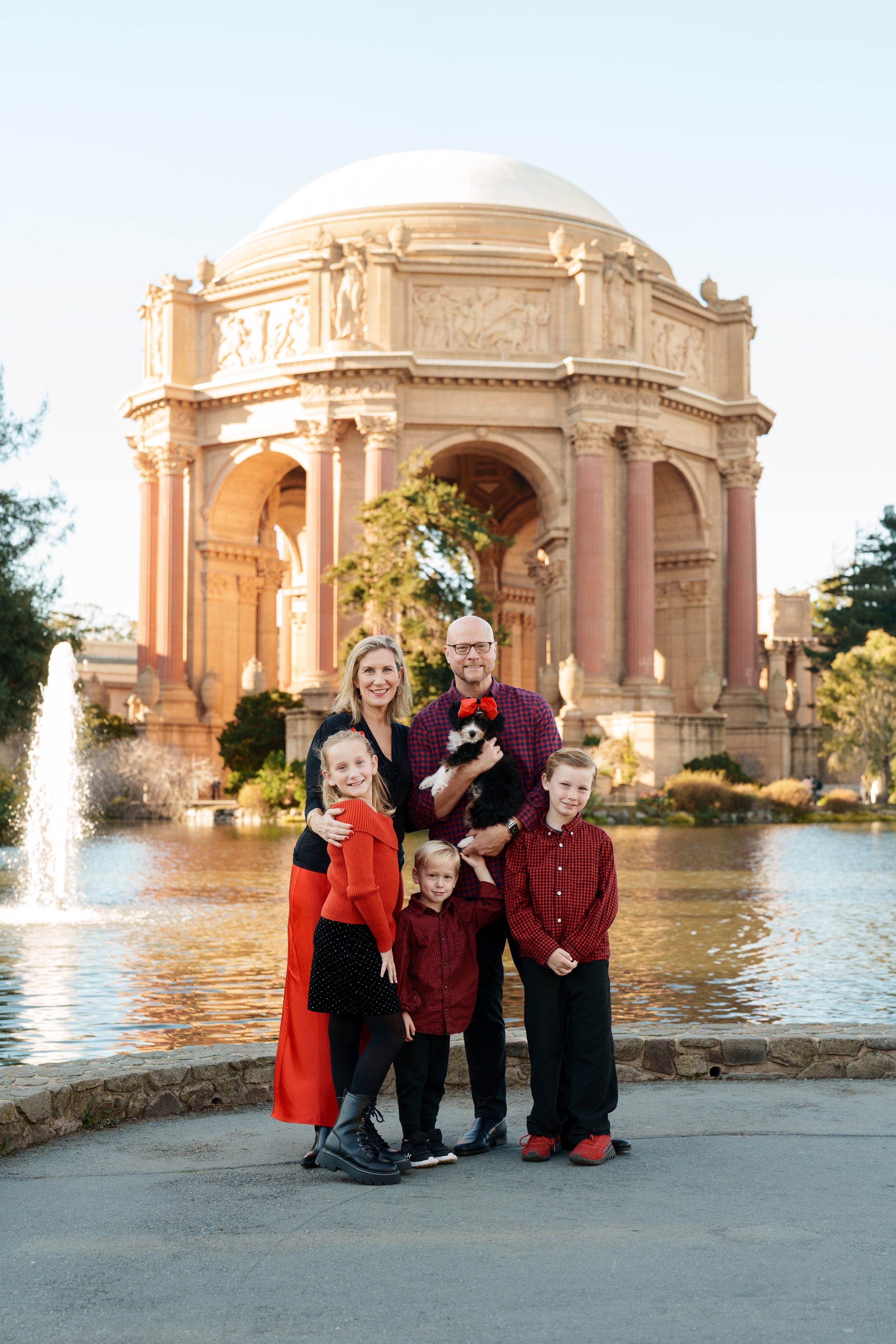 Bay Area family portrait of parents, daughter, two sons and a small dog in red and black holiday attire at the Palace of Fine
