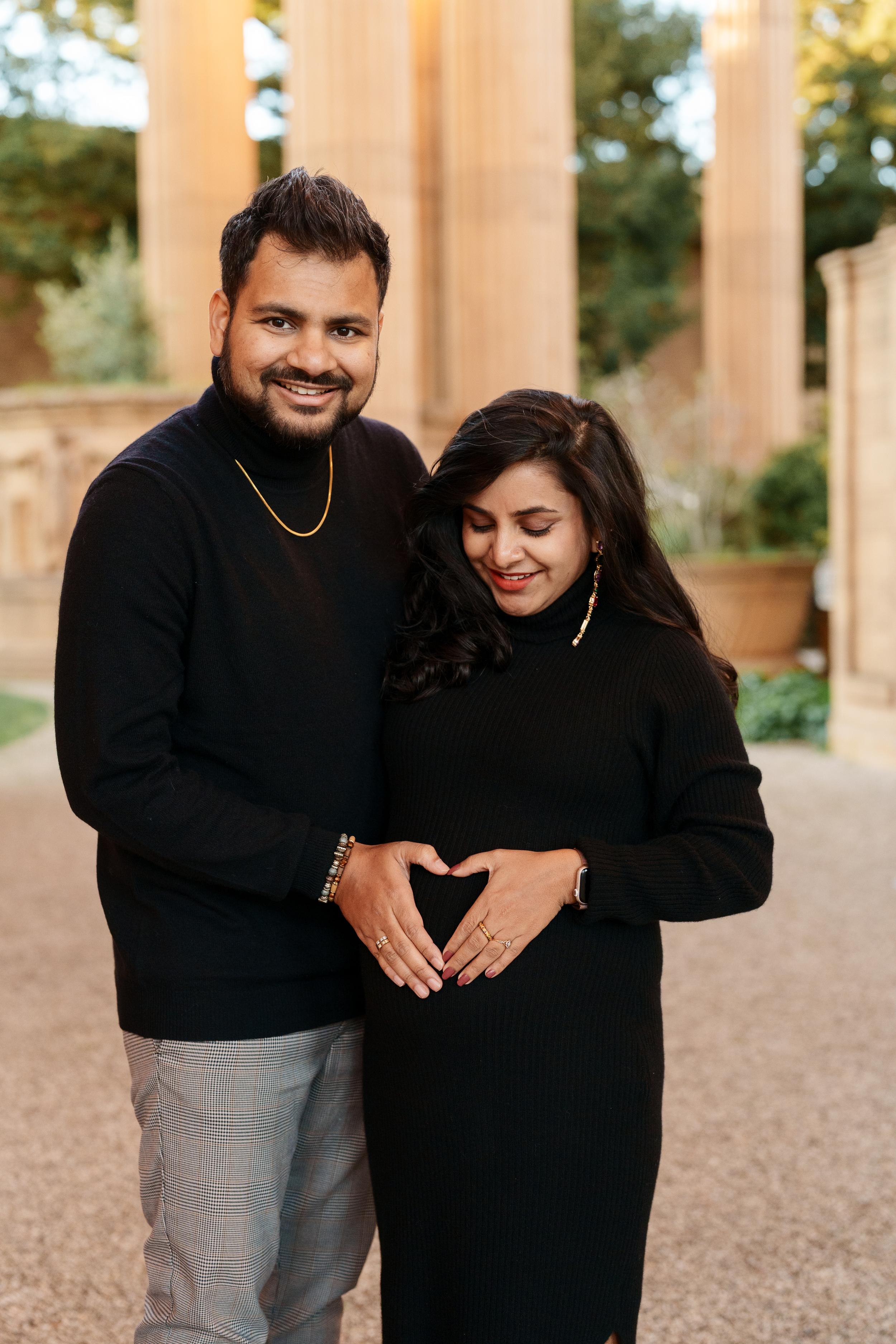 Bay Area couples maternity portrait of expecting parents in black attire forming a heart over baby bump near Palace of Fine